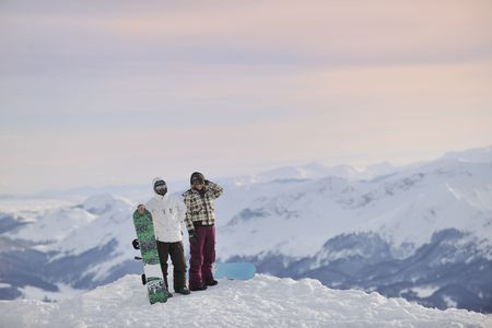 happy young snowboarder couple relax at top of mountain at beautiful sunny winter dayの写真素材