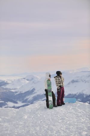 happy young snowboarder couple relax at top of mountain at beautiful sunny winter dayの写真素材