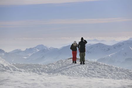happy young snowboarder couple relax at top of mountain at beautiful sunny winter dayの写真素材