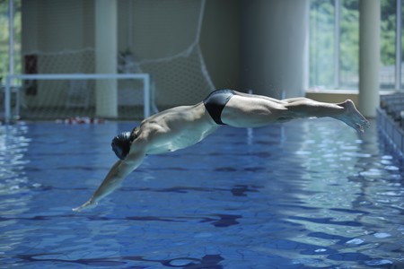 young swimmer on swim start at swimming pool ready for jump race and win