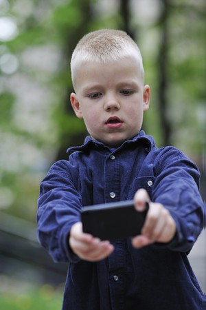 young blonde boy playing videogames outdoor in parkの写真素材