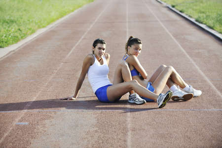 two girls relaxing on athletic race trackの写真素材