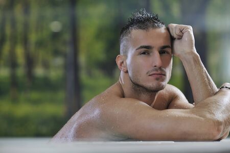 young healthy good looking macho man model athlete at hotel indoor poolの写真素材