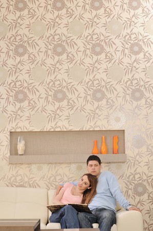 happy young couple looking old pictures in photo album at homeの写真素材