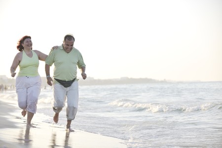 happy senior mature elderly people couple have romantic time on beach at sunset の写真素材