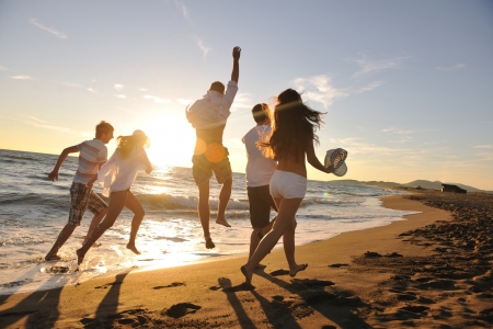 happy young people group have fun white running and jumping on beacz at sunset time