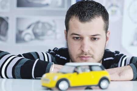 young businessman car designer posing indoor in casual clothing over big bright windowの写真素材