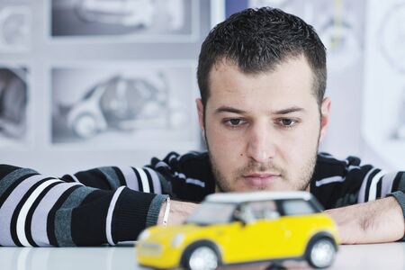 young businessman car designer posing indoor in casual clothing over big bright window