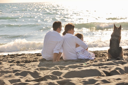 happy young family in white clothing have fun and play with beautiful dog at vacations on beautiful beach の写真素材