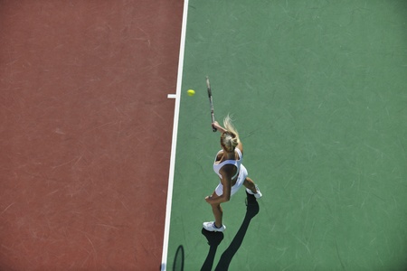 young fit woman play tennis outdoor on orange tennis field at early morningの写真素材