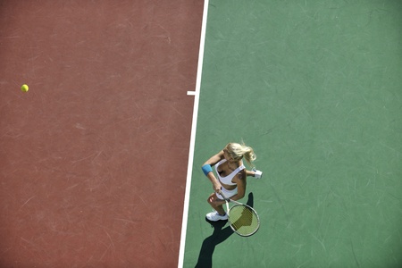 young fit woman play tennis outdoor on orange tennis field at early morningの写真素材