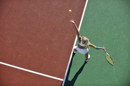 young fit woman play tennis outdoor on orange tennis field at early morningの写真素材