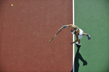 young fit woman play tennis outdoor on orange tennis field at early morningの写真素材