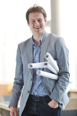 happy young architect business man portrait with paper blueprints planの写真素材
