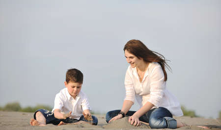 happy young mother  and son relaxing and play ind sand games on beach at summer seasonの写真素材