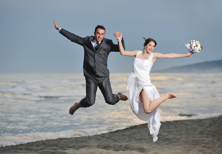 happy just married young couple celebrating and have fun at beautiful beach sunsetの写真素材