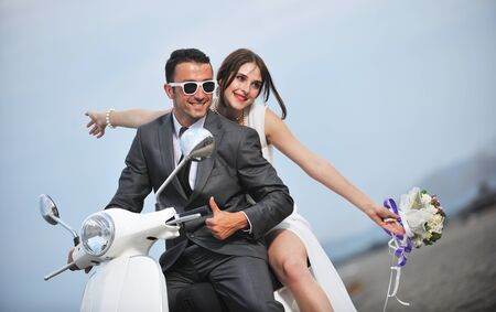 wedding sce of bride and groom just married couple on the beach ride white scooter and have funの写真素材