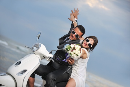wedding sce of bride and groom just married couple on the beach ride white scooter and have funの写真素材