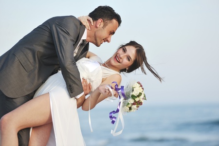 happy just married young couple celebrating and have fun at beautiful beach sunsetの写真素材