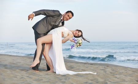happy just married young couple celebrating and have fun at beautiful beach sunsetの写真素材