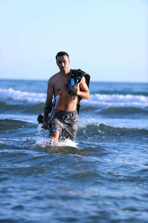Portrait of a strong young  surf  man at beach on sunset in a contemplative mood with a surfboardの写真素材