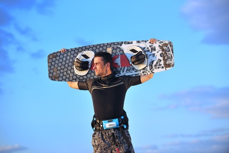 Portrait of a strong young  surf  man at beach on sunset in a contemplative mood with a surfboardの写真素材