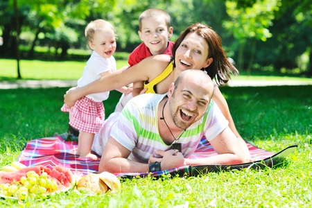 happy young couple with their children have fun at beautiful park outdoor in nature