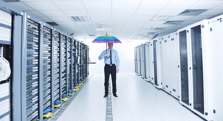 young handsome business man  engineer in 
businessman hold  rainbow colored umbrella in server datacenter room  and representing security and antivirus sofware protection conceptの写真素材