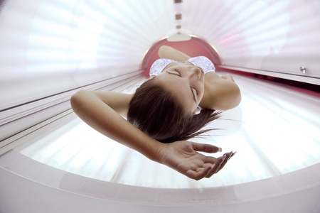 Beautiful young woman have tanning skin treatment in modern solariumの写真素材