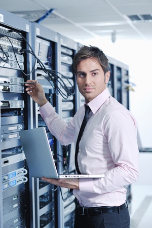 young engeneer business man with thin modern aluminium laptop in network server room