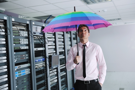 young handsome business man  engineer in 
businessman hold  rainbow colored umbrella in server datacenter room  and representing security and antivirus sofware protection conceptの写真素材