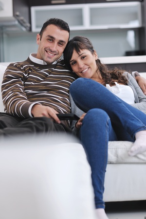 Relaxed young  couple watching tv at home in bright living roomの写真素材