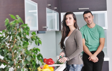 happy young couple have fun in  modern kitchen indoor  while preparing fresh fruits and vegetables food saladの写真素材