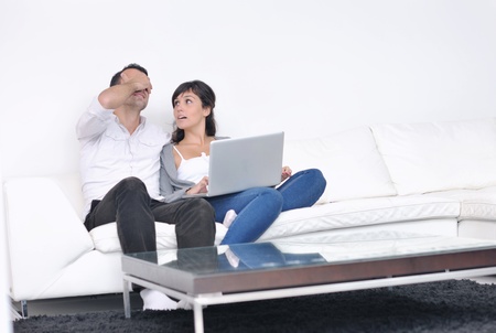 joyful couple relax and work on laptop computer at modern living room indoor homeの写真素材