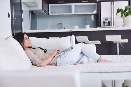 relaxed young woman working on laptop computer in bright  home indoorのeditorial素材