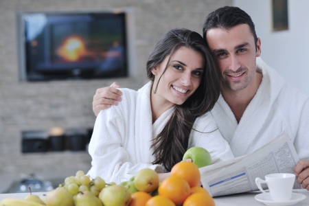 young family couple read newspaper at kitchen in morning with  fresh breakfast  fruits food and coffee drink on tableの写真素材