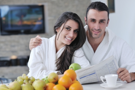 young family couple read newspaper at kitchen in morning with  fresh breakfast  fruits food and coffee drink on tableの写真素材