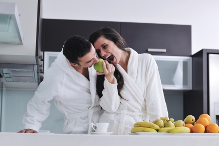 happy young couple have fun in  modern kitchen indoor  while preparing fresh fruits and vegetables food saladの写真素材