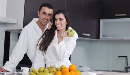 happy young couple have fun in  modern kitchen indoor  while preparing fresh fruits and vegetables food saladの写真素材