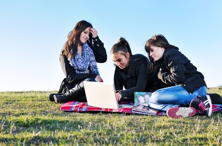 group of teen girl woman outdoor have fun and study homework on laptop computerの写真素材
