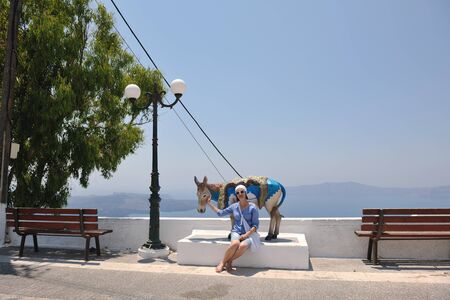 Beautiful young Greek woman in fashion clothes have fun at n the streets of Oia, Santorini, Greeceの写真素材