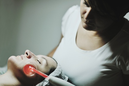 Young beautiful woman receiving cosmetic facial mask in spa beauty salon and relax