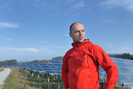 Male engineer at work place, solar panels plant industy in background