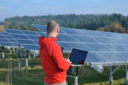 business man  engineer using laptop at solar panels plant eco energy field  in backgroundの写真素材