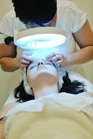 Young beautiful woman receiving cosmetic facial mask in spa beauty salon and relax