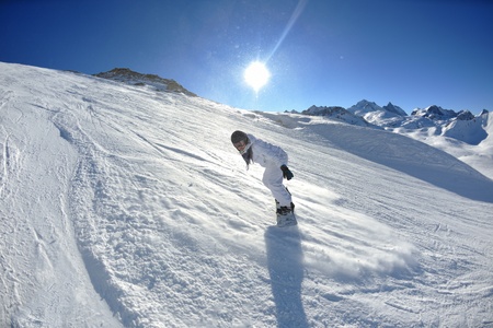 skier skiing downhill on fresh powder snow  with sun and mountains in background