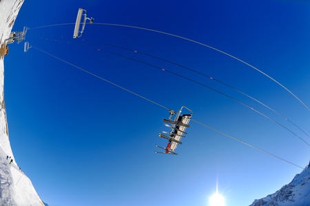 Ski lift - happy skiers use vertical transport  on ski vacation at sunny winter snow day