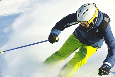 skier skiing downhill on fresh powder snow  with sun and mountains in backgroundの写真素材