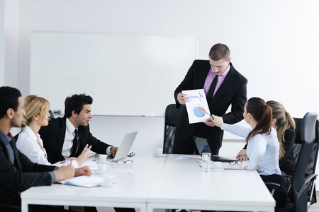 Group of young business people sitting in board room during meeting and discussing with paperworkの写真素材