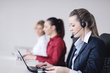 Pretty young business woman group with headphones smiling at you against white backgroundの写真素材
